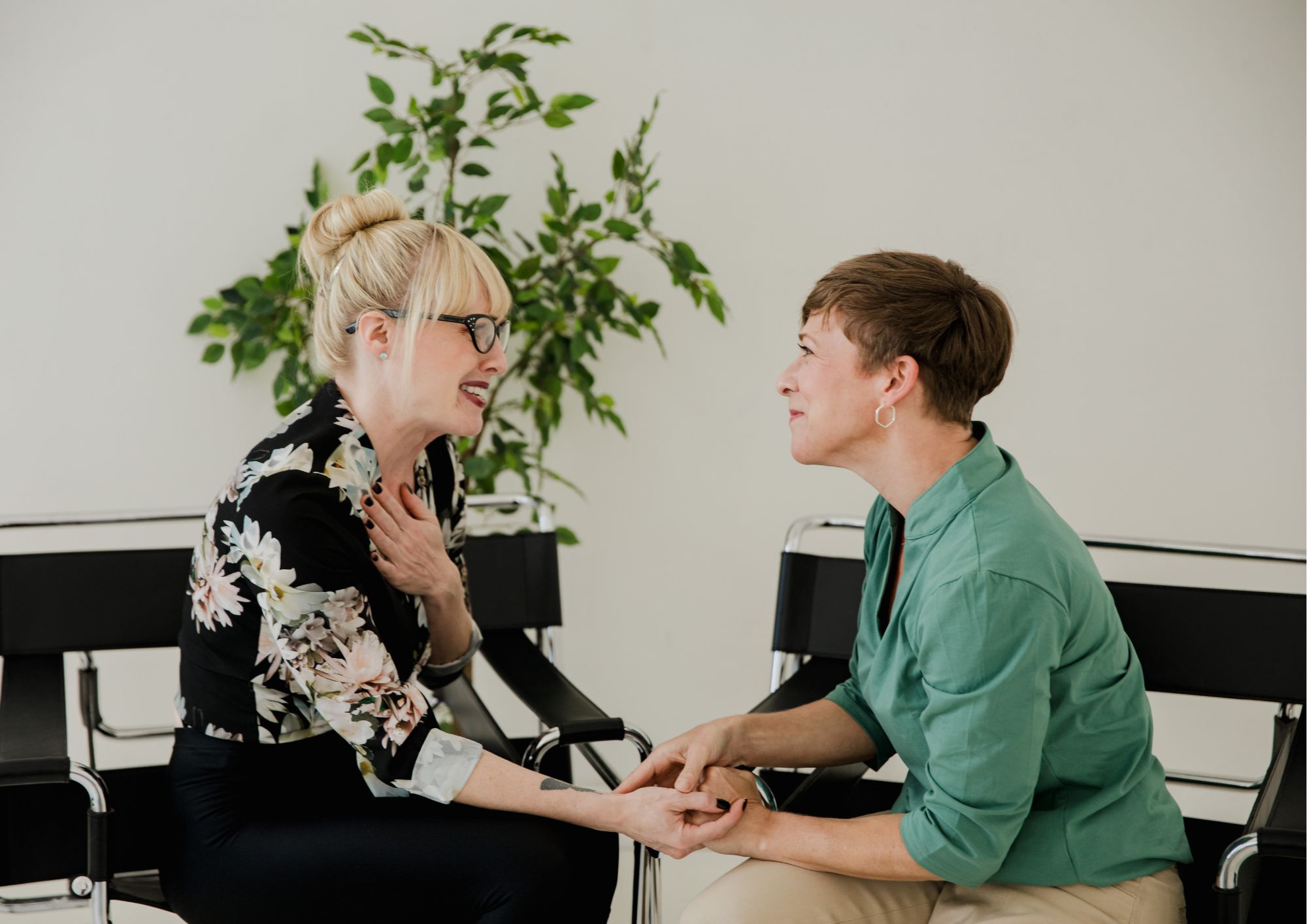 Coach and client are holding hands in a powerful moment of empathy and connection during their coaching conversation, demonstrating deep trust and safety in the coaching relationship