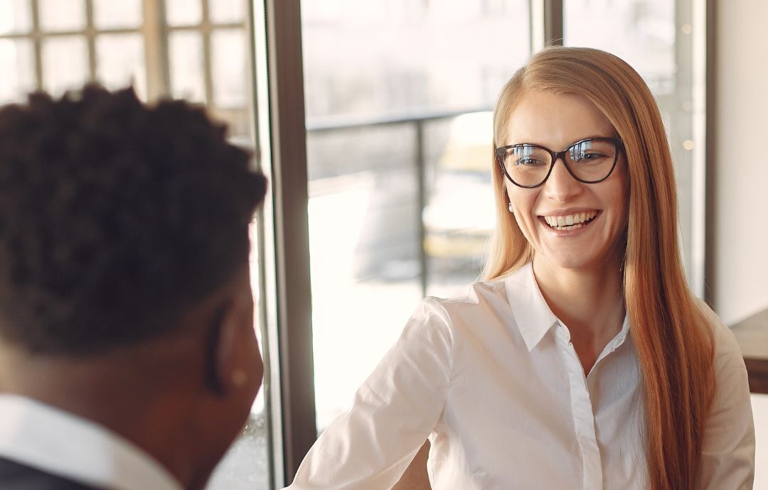Female coach in a conversation with a male leader demonstrating a coaching mindset and ICF Core Competencies during a face-to-face session in the workplace