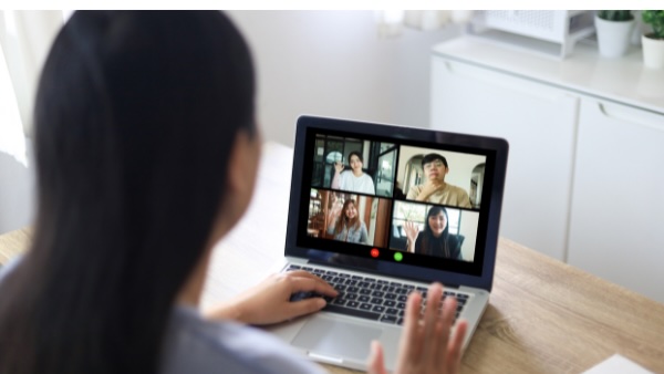 Female coach leading a virtual workplace coaching session, with employees visible on a laptop screen