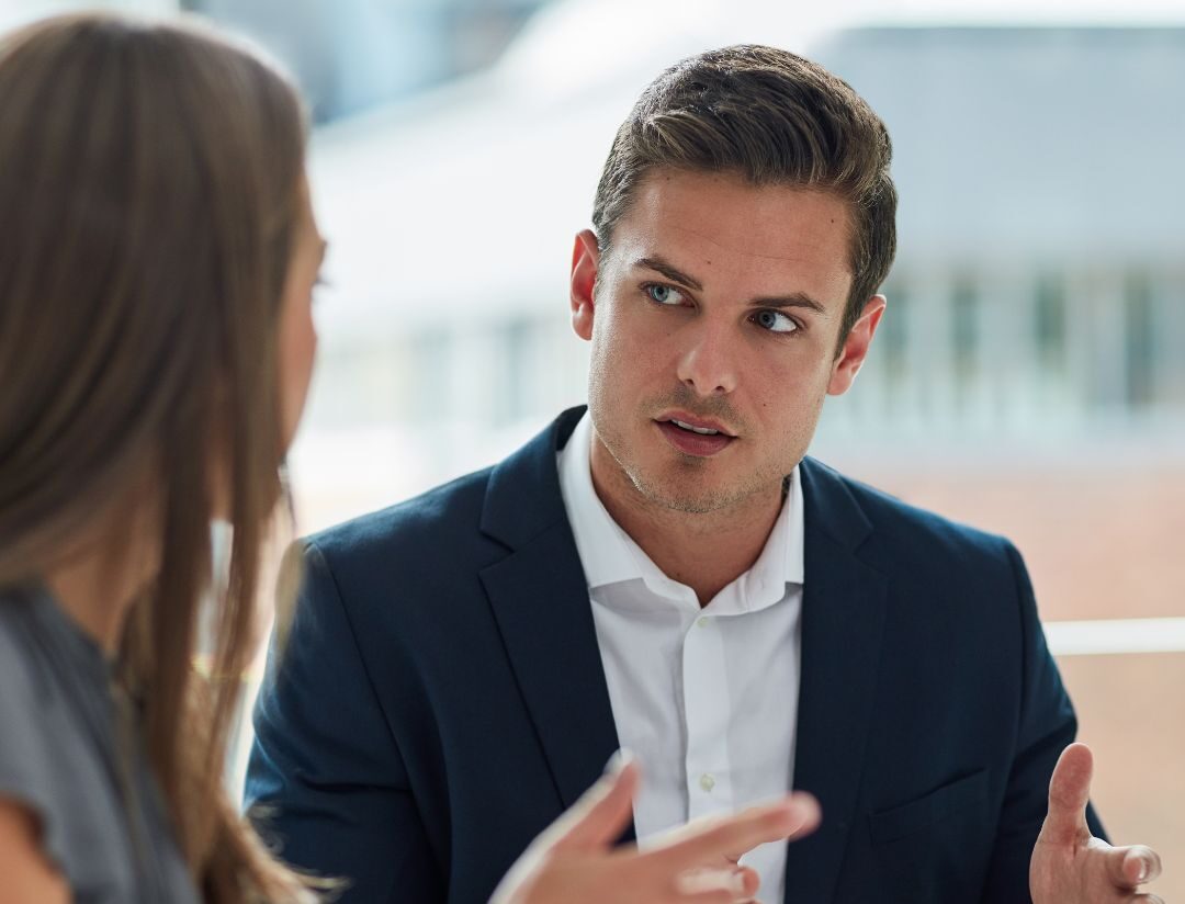 Male coach in a face-to-face conversation with a female leader demonstrating honesty and direct communication as an essential ICF Core Competency in coaching