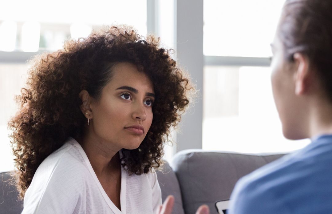 Female coach acting as a thinking partner and demonstrating active listening and reflective inquiry in a face-to-face coaching session with a female leader